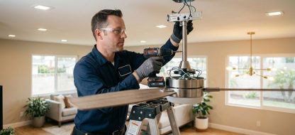 Professional electrician installing a ceiling fan in a modern Anaheim living room.